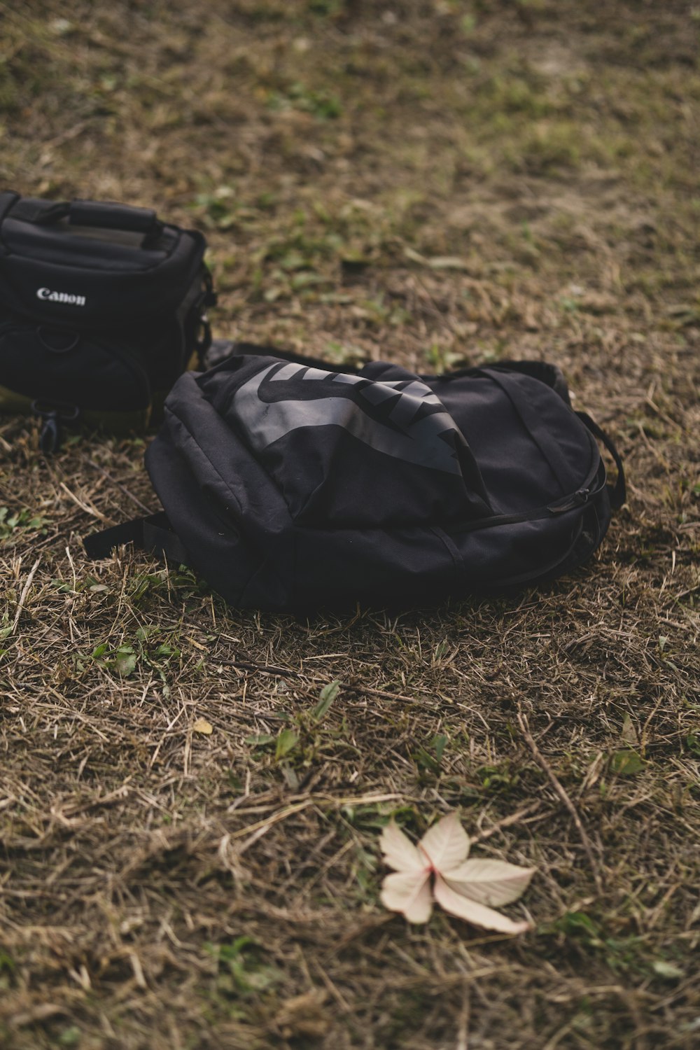a black backpack sitting on top of a grass covered field