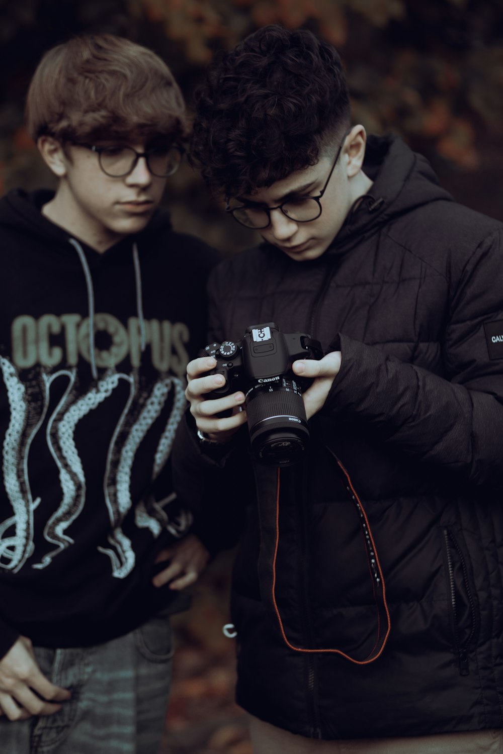 two young men standing next to each other looking at a camera