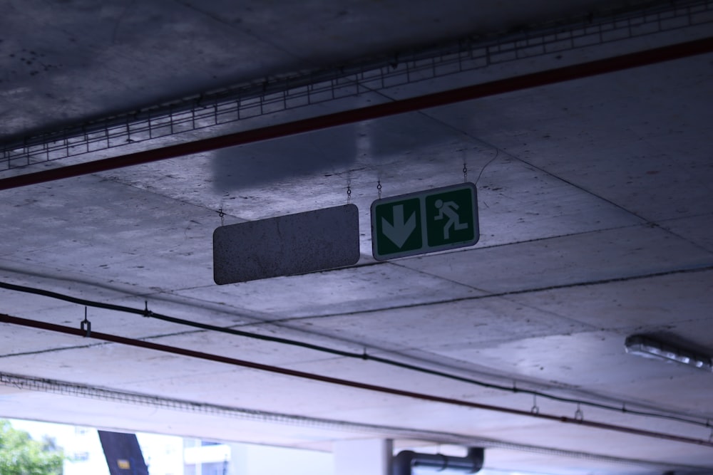 a green sign hanging from the ceiling of a parking garage