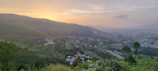A panoramic view of eco-friendly housing nestled in a green valley at sunset.