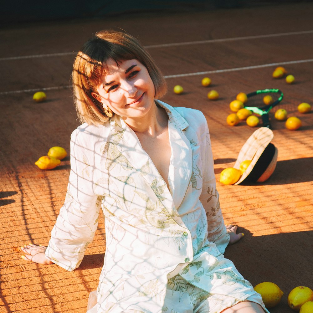 a woman sitting on a tennis court surrounded by tennis balls