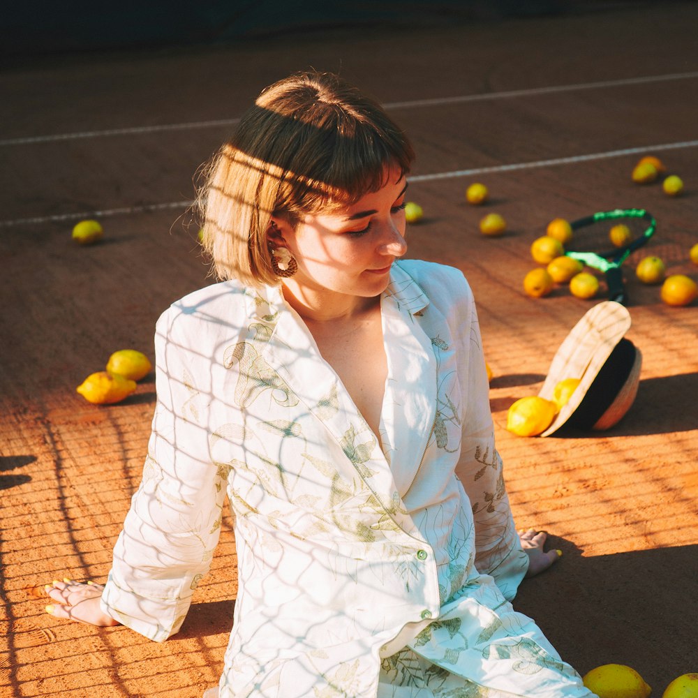 a woman sitting on a tennis court surrounded by tennis balls