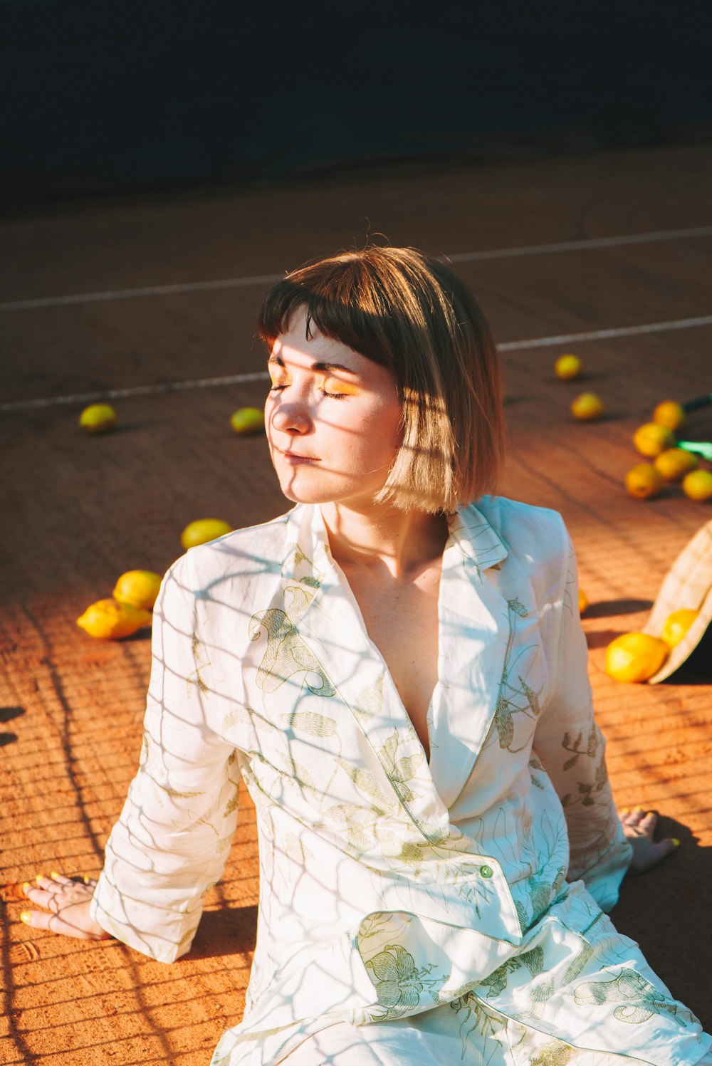 a woman in a white dress sitting on a tennis court