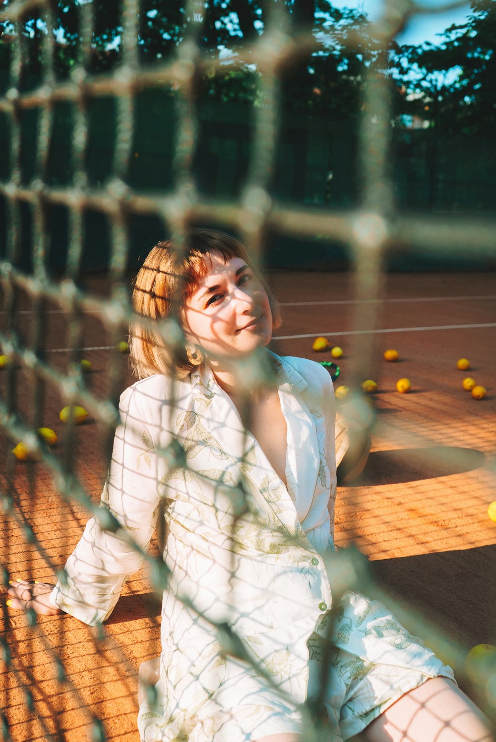 a woman sitting on a tennis court next to a net