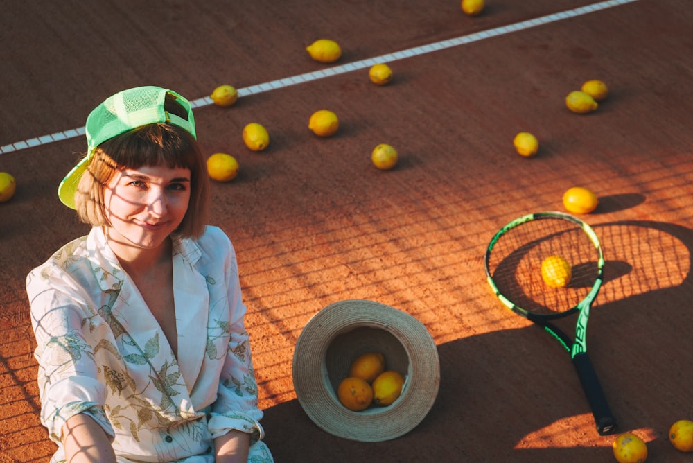 a woman sitting on a tennis court next to a tennis racket