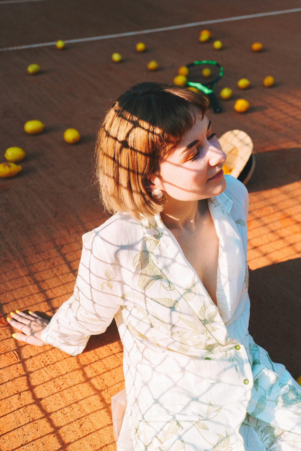 a woman sitting on a tennis court holding a tennis racquet