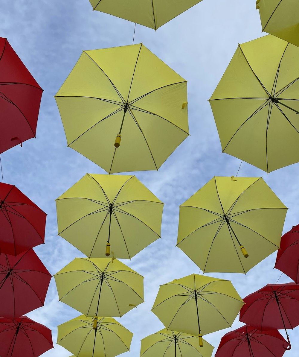 a group of yellow and red umbrellas floating in the air