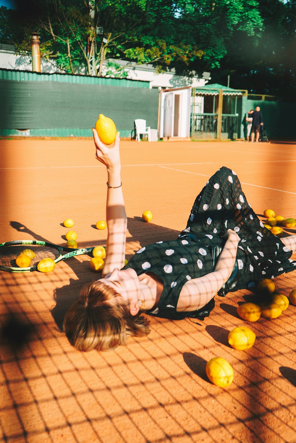 a woman laying on the ground with a tennis racket and ball