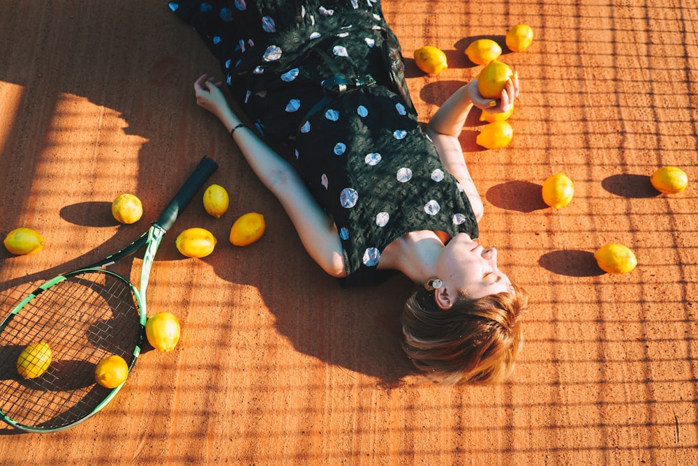 a woman laying on the ground with a tennis racket