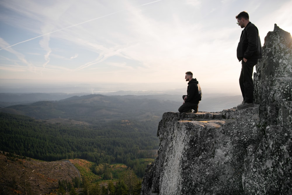 a couple of men standing on top of a cliff