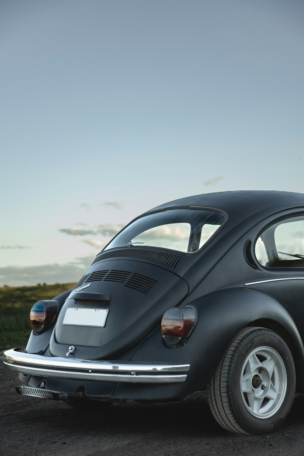 a black vw bug sitting on top of a dirt road