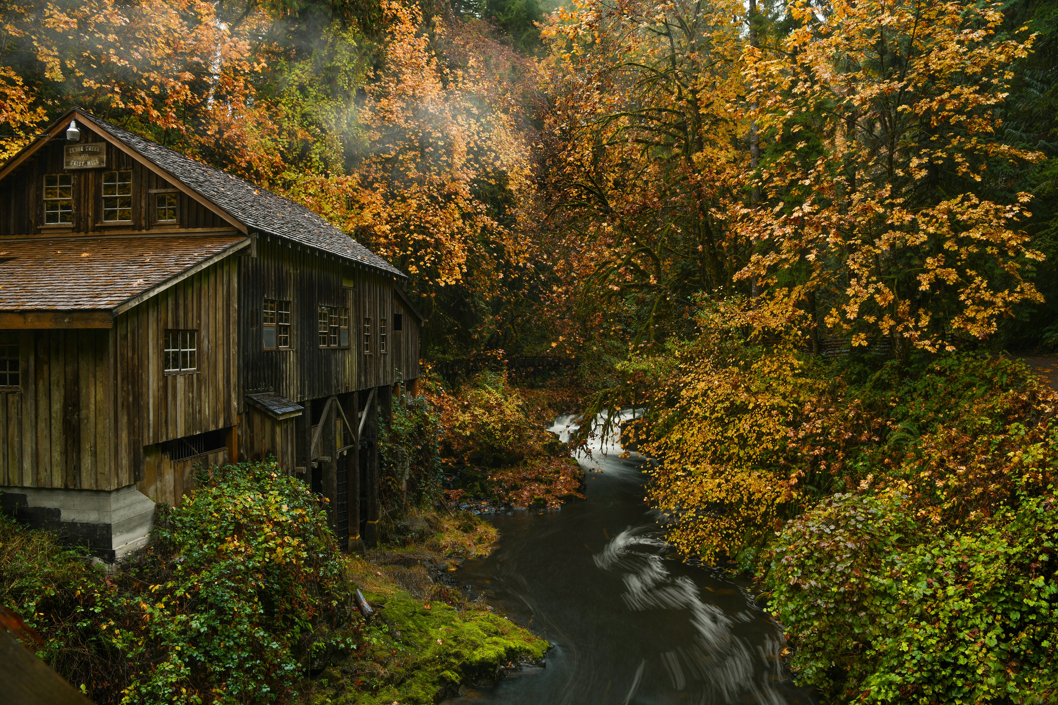 a wooden building surrounded by trees and water