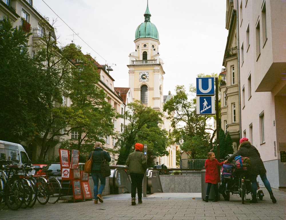 a group of people walking down a street next to tall buildings