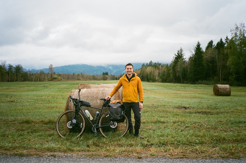 um homem de pé ao lado de uma bicicleta em um campo