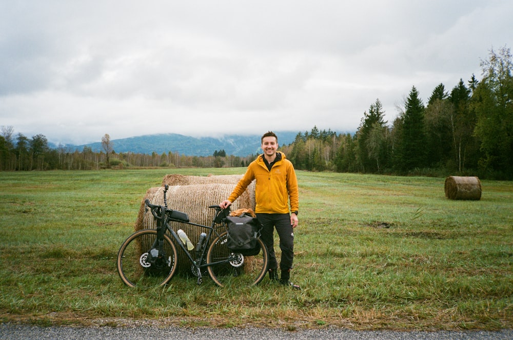 a man standing next to a bike in a field