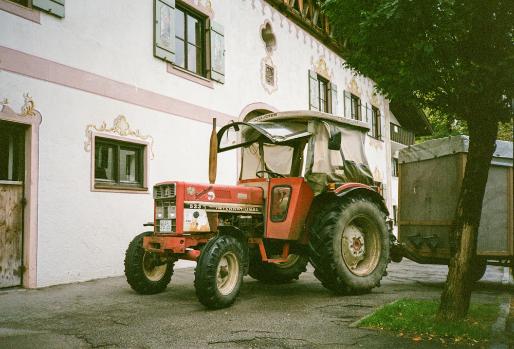 a red tractor parked in front of a white building