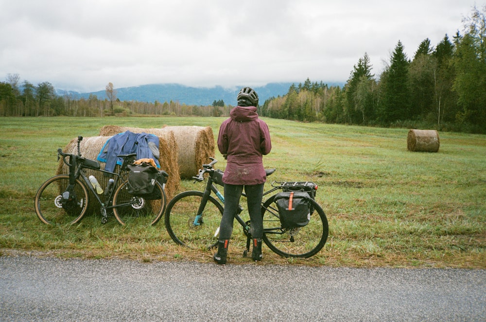 a person standing next to a bike near hay bales