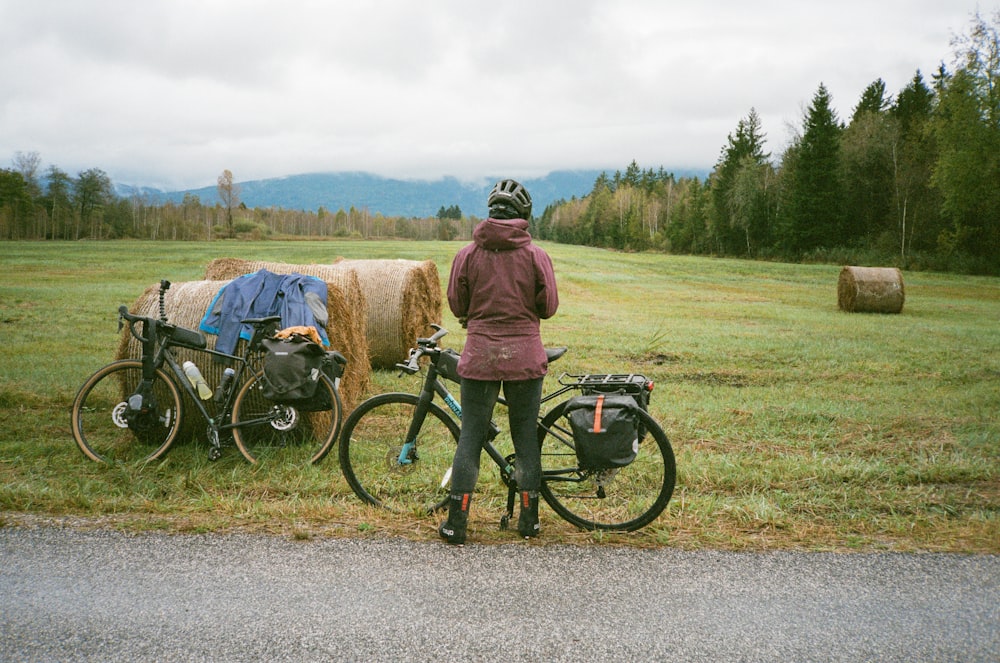 干し草の俵の近くで自転車の隣に立っている人