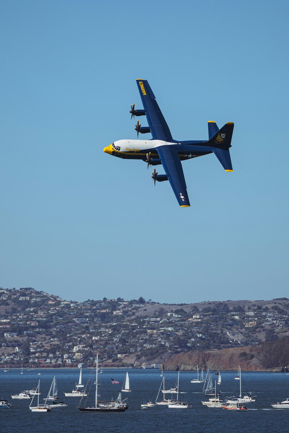 a blue and white plane flying over a body of water