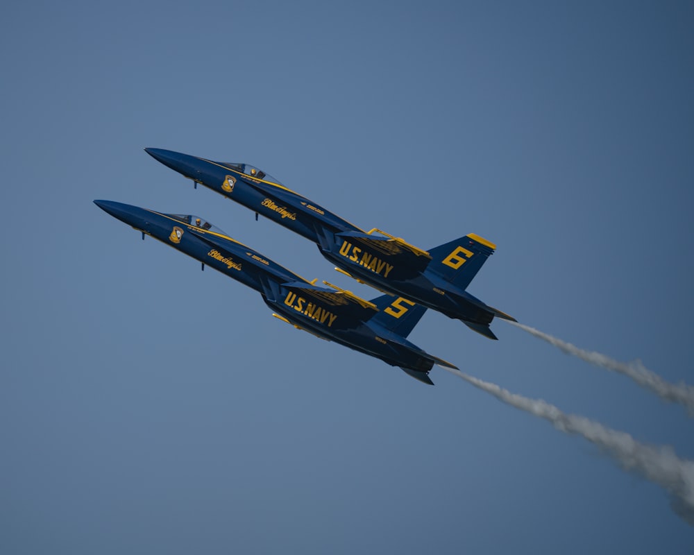 two blue and yellow jets flying in the sky