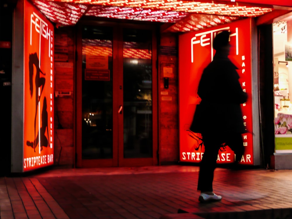 a man walking down a sidewalk in front of a building