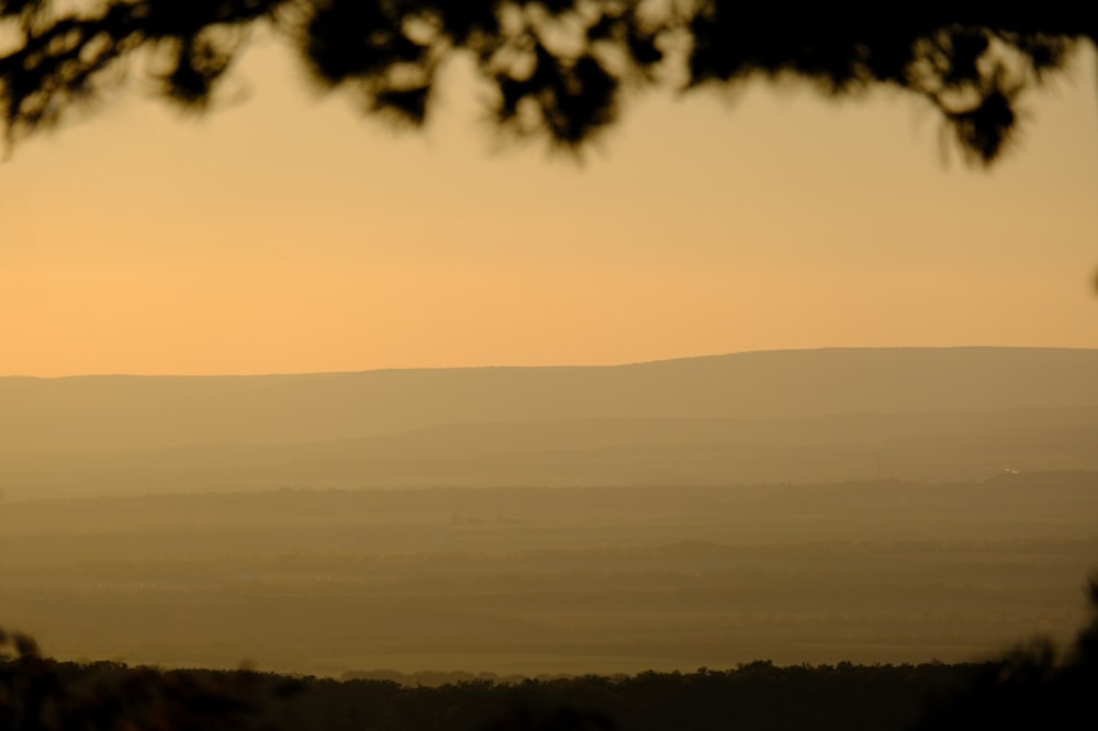 the sun is setting over the mountains in the distance