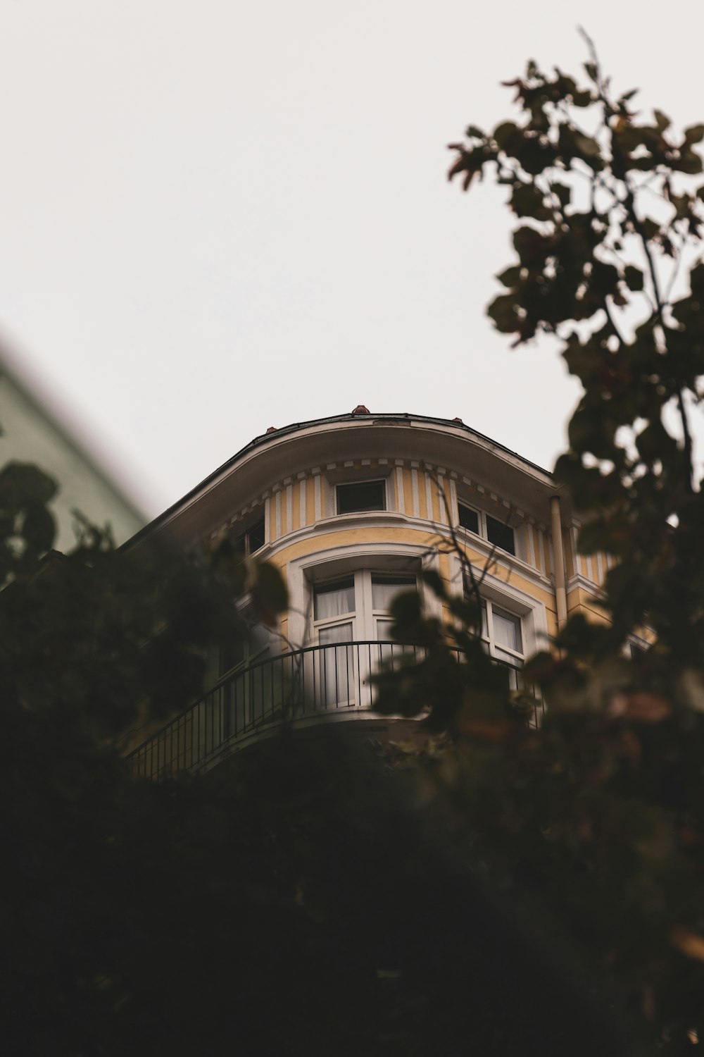 a building with a balcony and a tree in front of it