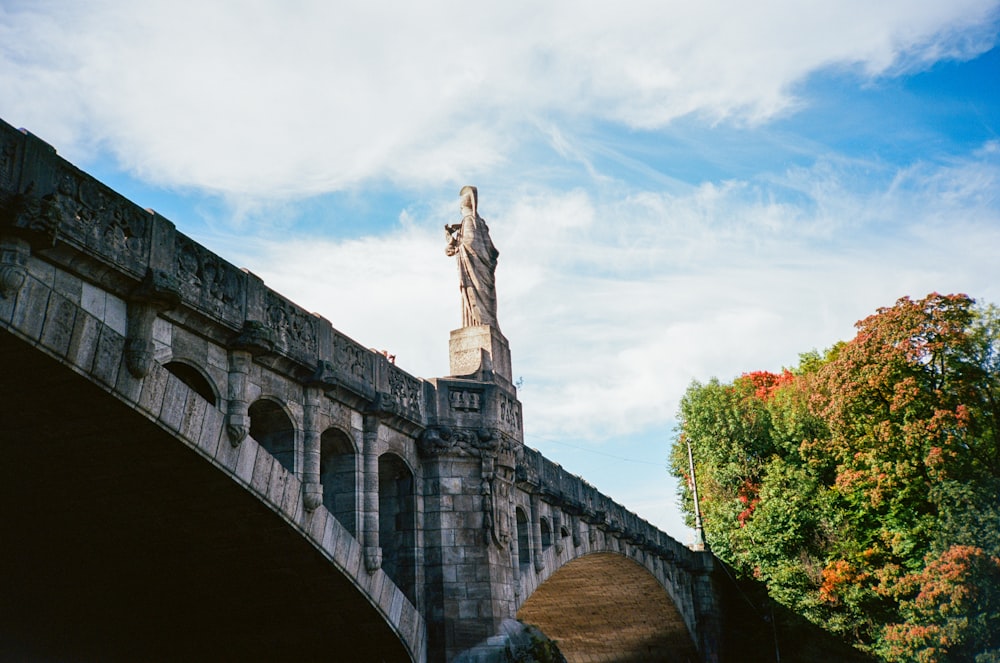 Una estatua en la parte superior de un puente con un fondo de cielo