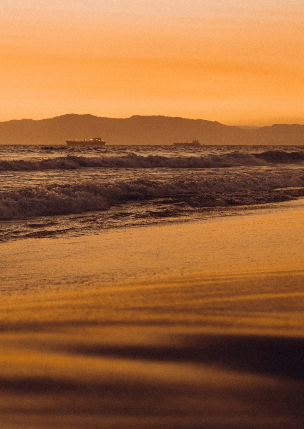 a person walking on the beach carrying a surfboard