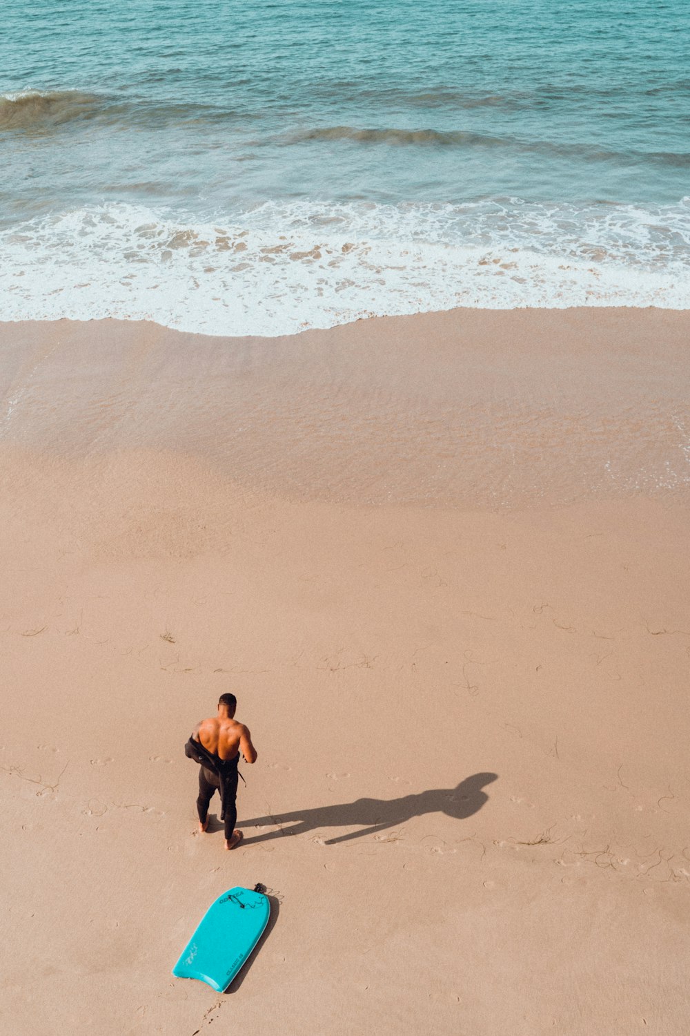 a man standing on top of a sandy beach next to the ocean