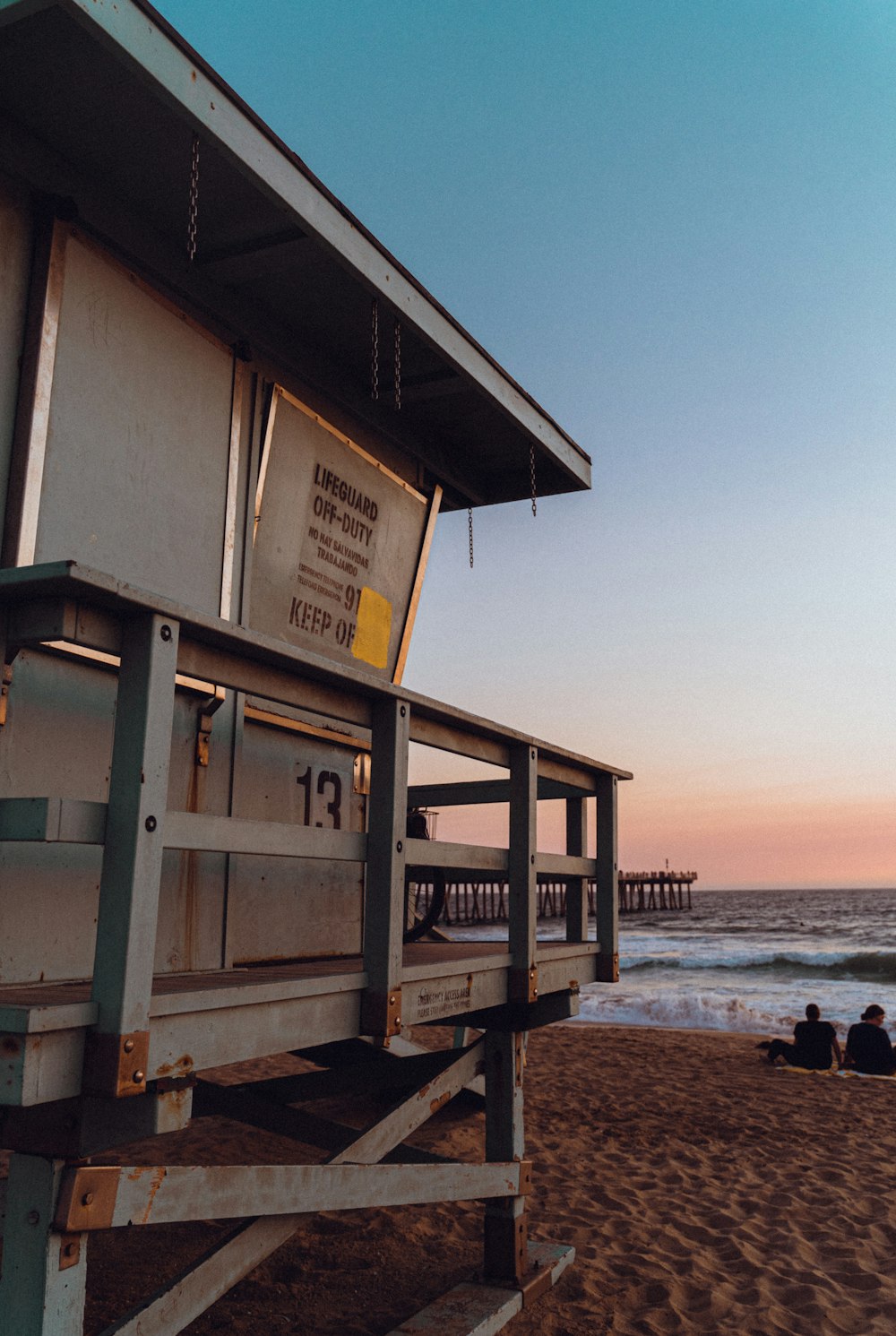 a lifeguard station sitting on the beach at sunset