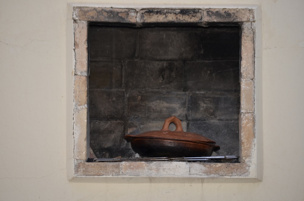 a wooden bowl sitting in a window of a brick wall