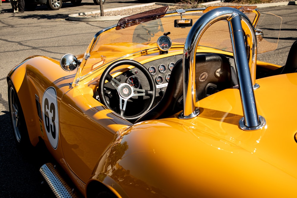 a close up of a yellow sports car with a steering wheel