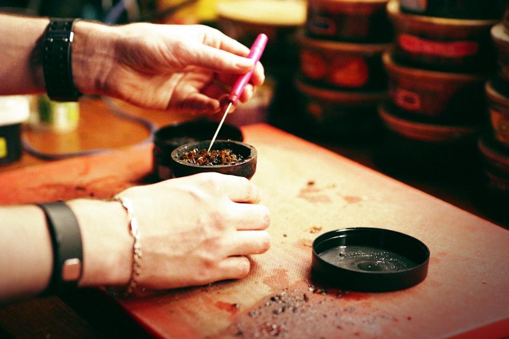 a person holding a spoon over a bowl of food