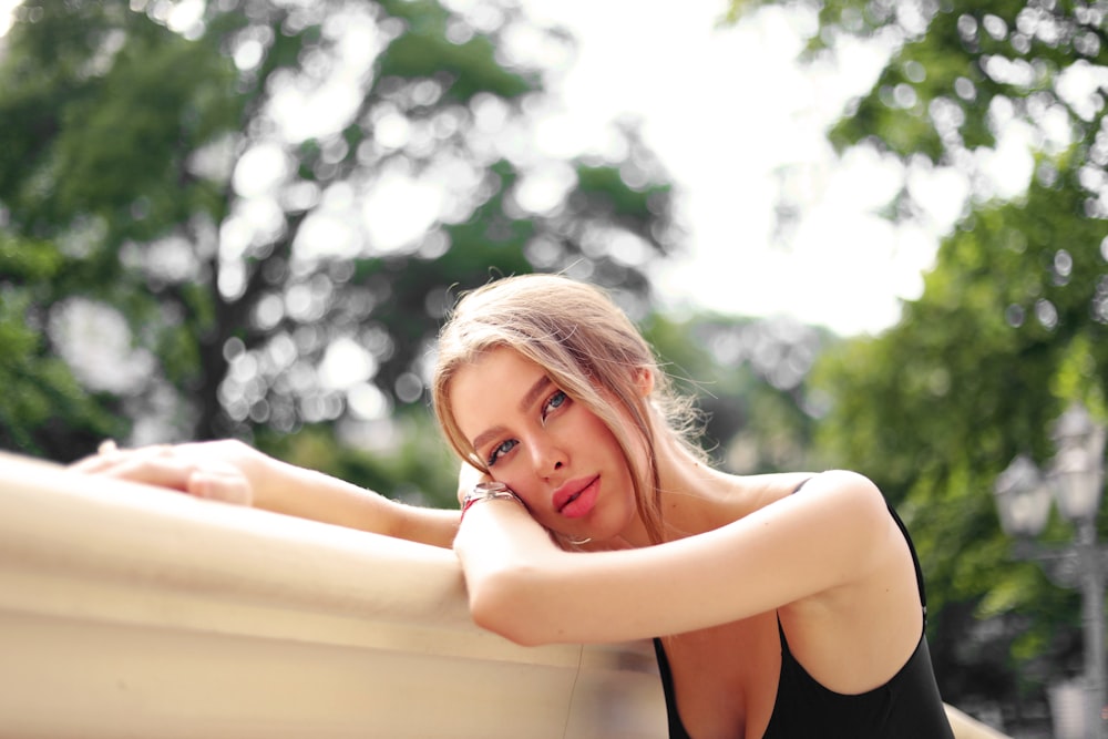 a woman leaning against a wall with her hand on her chin