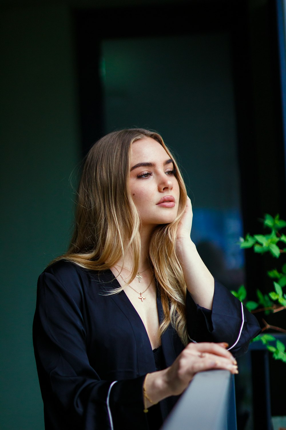 a woman leaning against a wall with her hand on her head