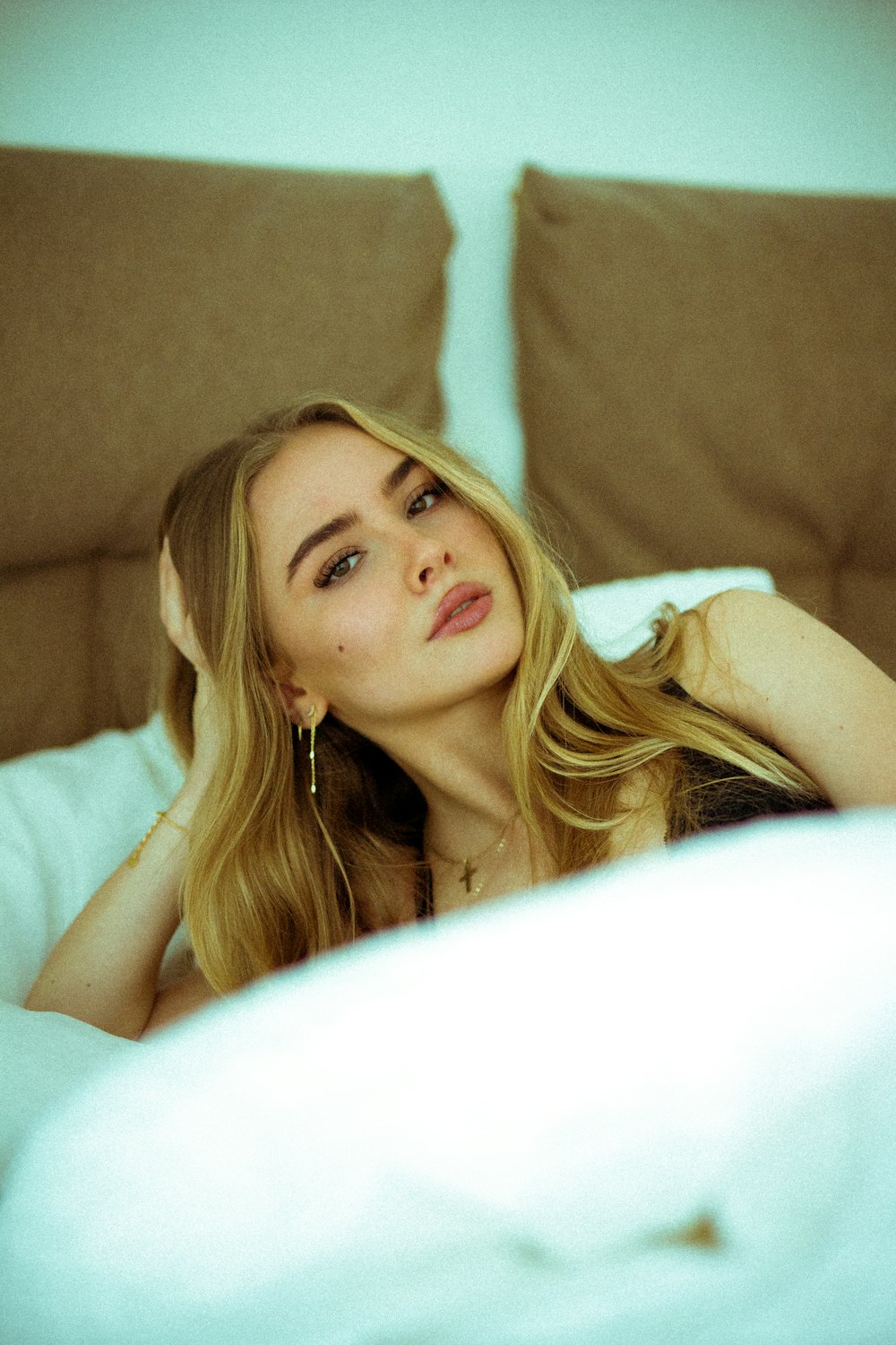 a woman laying in bed with her hand on her head