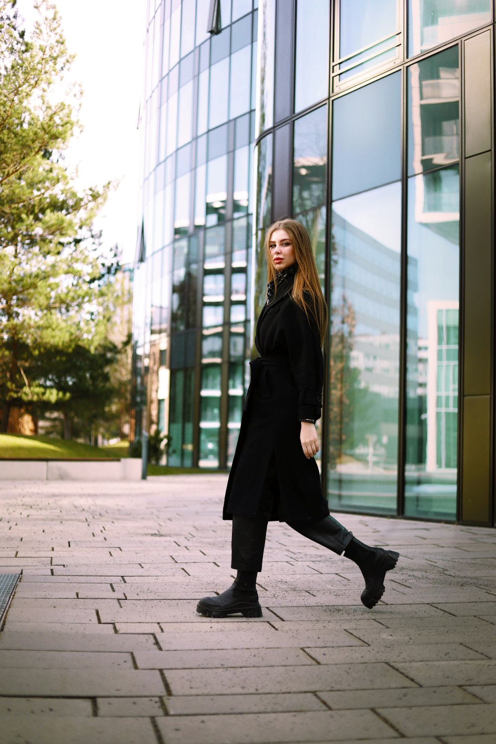 a woman in a black coat is walking down the street