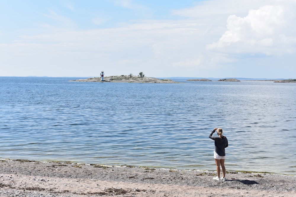 a person standing on a beach looking at the water