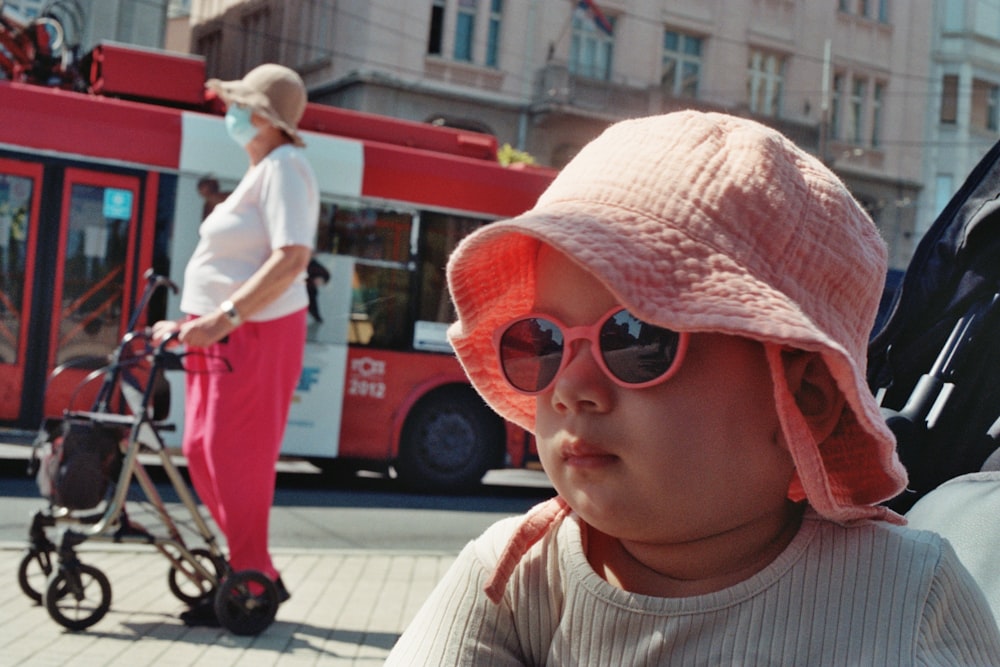 a small child wearing a pink hat and sunglasses