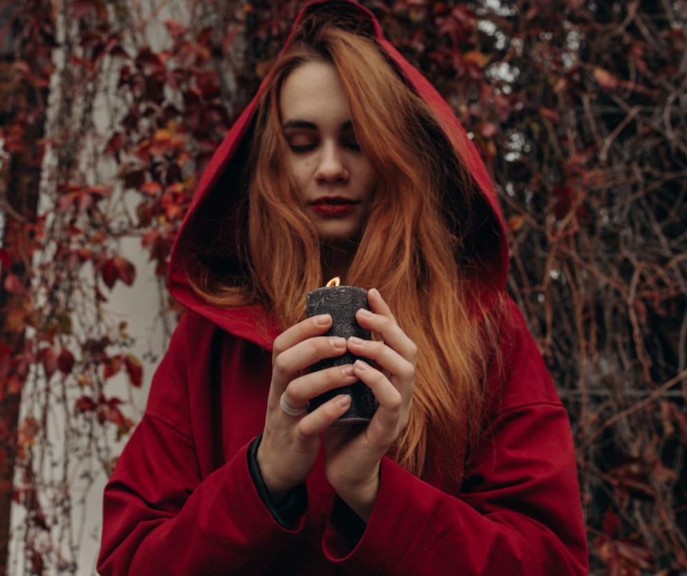 Una donna in una felpa rossa con cappuccio che tiene un accendino