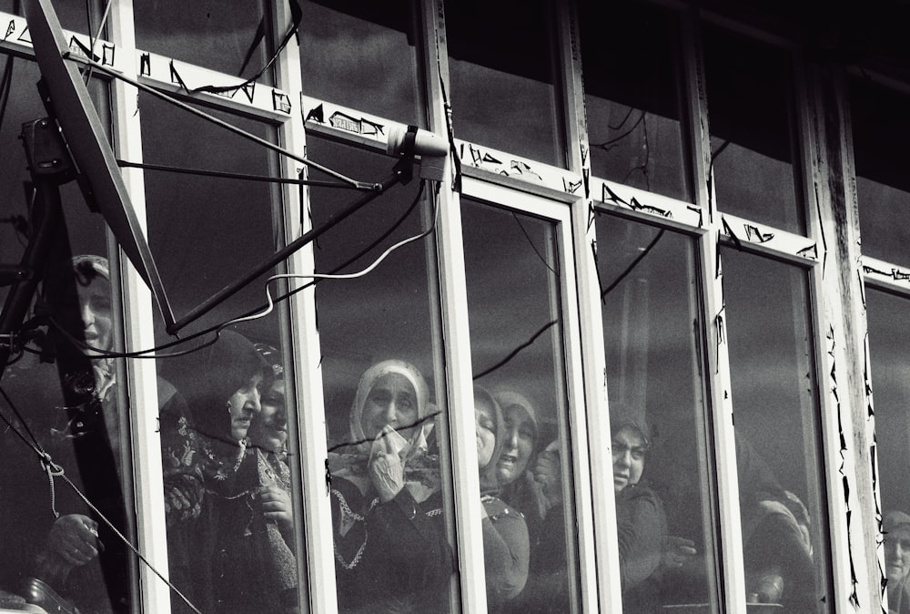a black and white photo of a group of people looking out a window