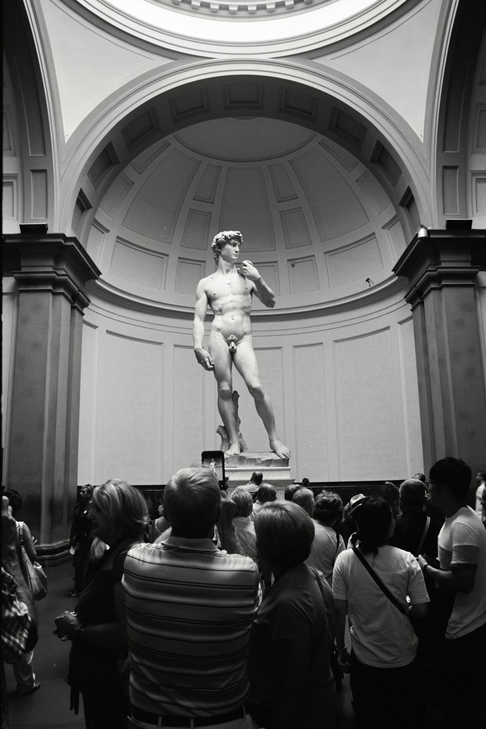 a crowd of people standing around a statue of a man