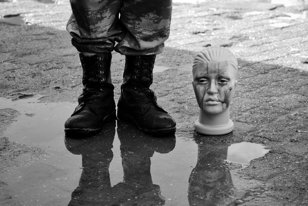 a black and white photo of a person standing next to a statue