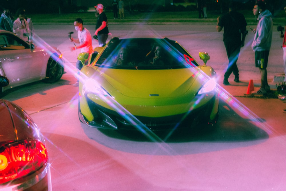 a group of people standing around a yellow sports car