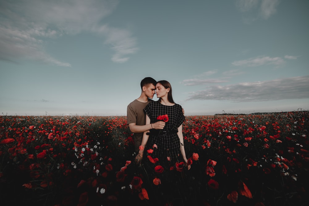 a man and a woman standing in a field of flowers