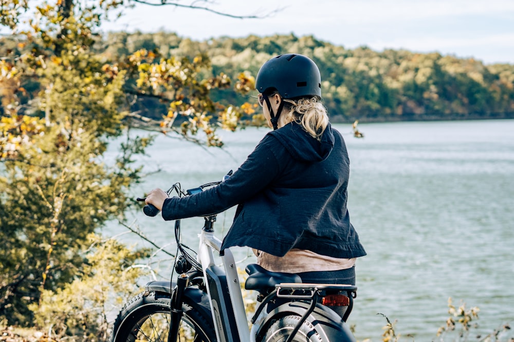a woman riding a bike next to a lake