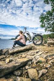 a woman sitting on a rock next to a bike