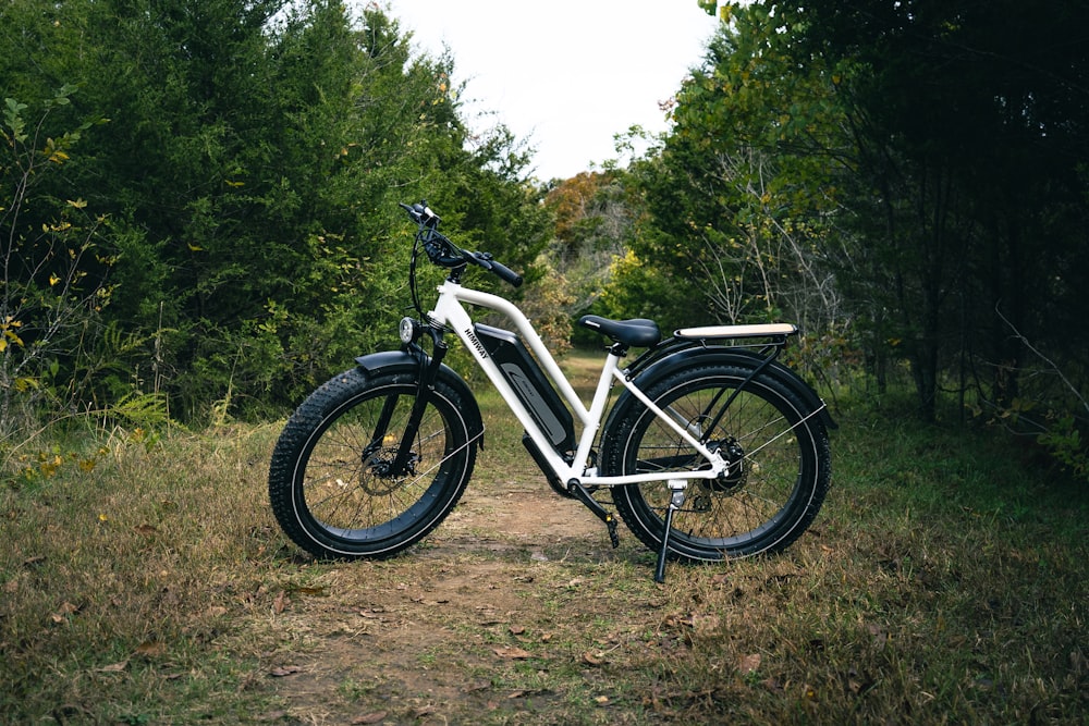 a bicycle parked on a dirt path in the woods