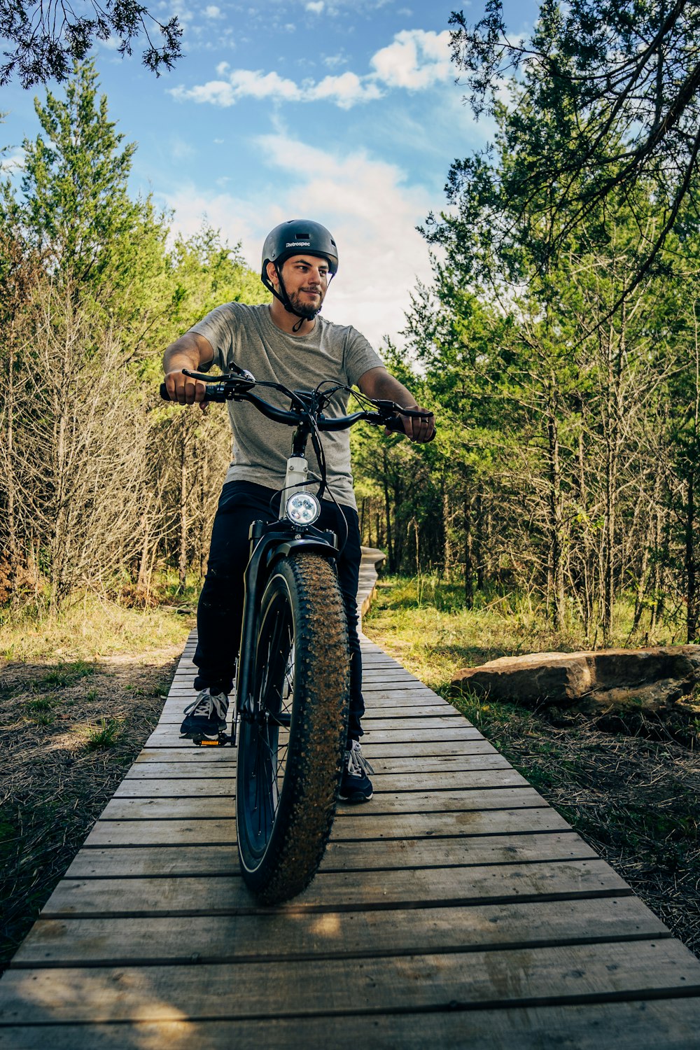 a man riding a bike across a wooden bridge